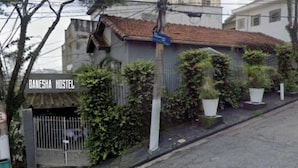 A hostel named Banesha Hostel with a gated entrance, surrounded by greenery and a sloped street. - Banesha Hostel (São Paulo)