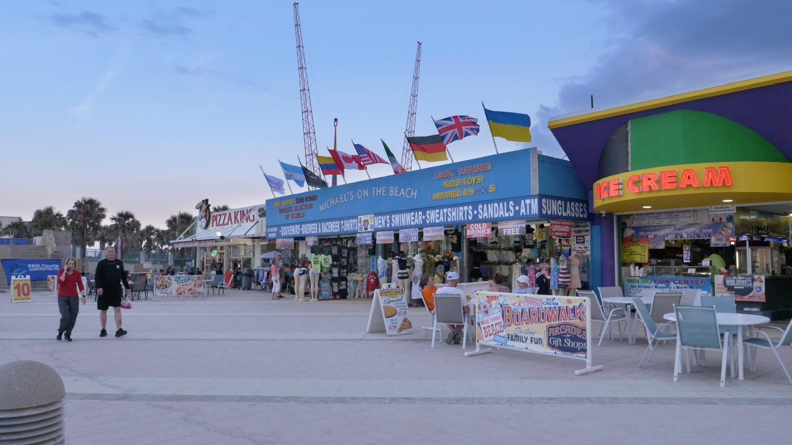 A boardwalk with shops, including a pizza place and an ice cream shop, and flags of various countries.