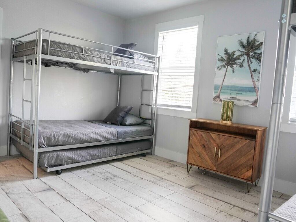 A bunk bed room with a wooden cabinet and a picture of palm trees.