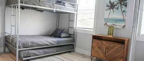 A bunk bed room with a wooden cabinet and a picture of palm trees.