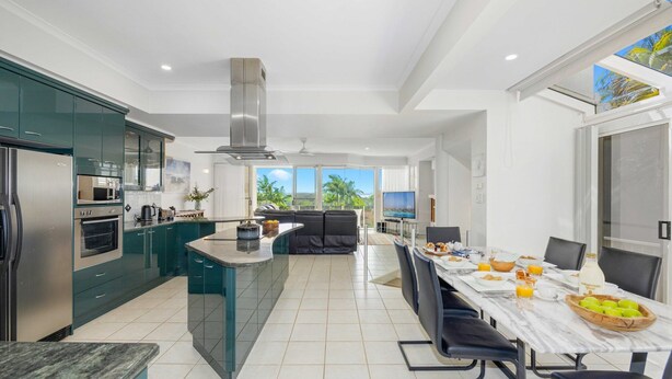 Una cocina moderna con una isla central, un comedor con vistas y un ventanal grande.