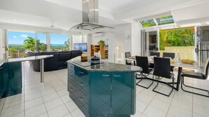 Una cocina moderna con una isla central, un área de comedor con mesa y sillas, y un ventanal que ofrece vistas al exterior.