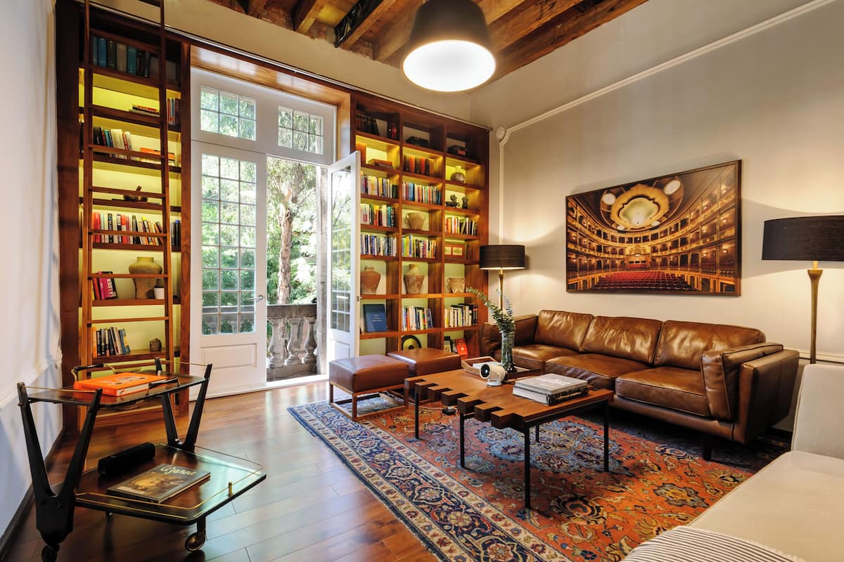 Uma sala de estar acolhedora, com um sofá de couro, uma mesa de centro e uma estante repleta de livros.