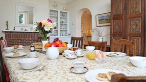 A dining room with a table set for breakfast, including bowls, cups, and a fruit bowl.