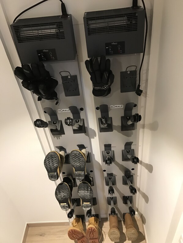 A wall-mounted shoe rack with multiple pairs of shoes and gloves.