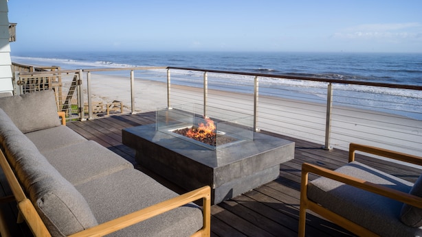Eine Terrasse mit Feuerstelle, Sitzgelegenheiten und Blick auf den Ozean.