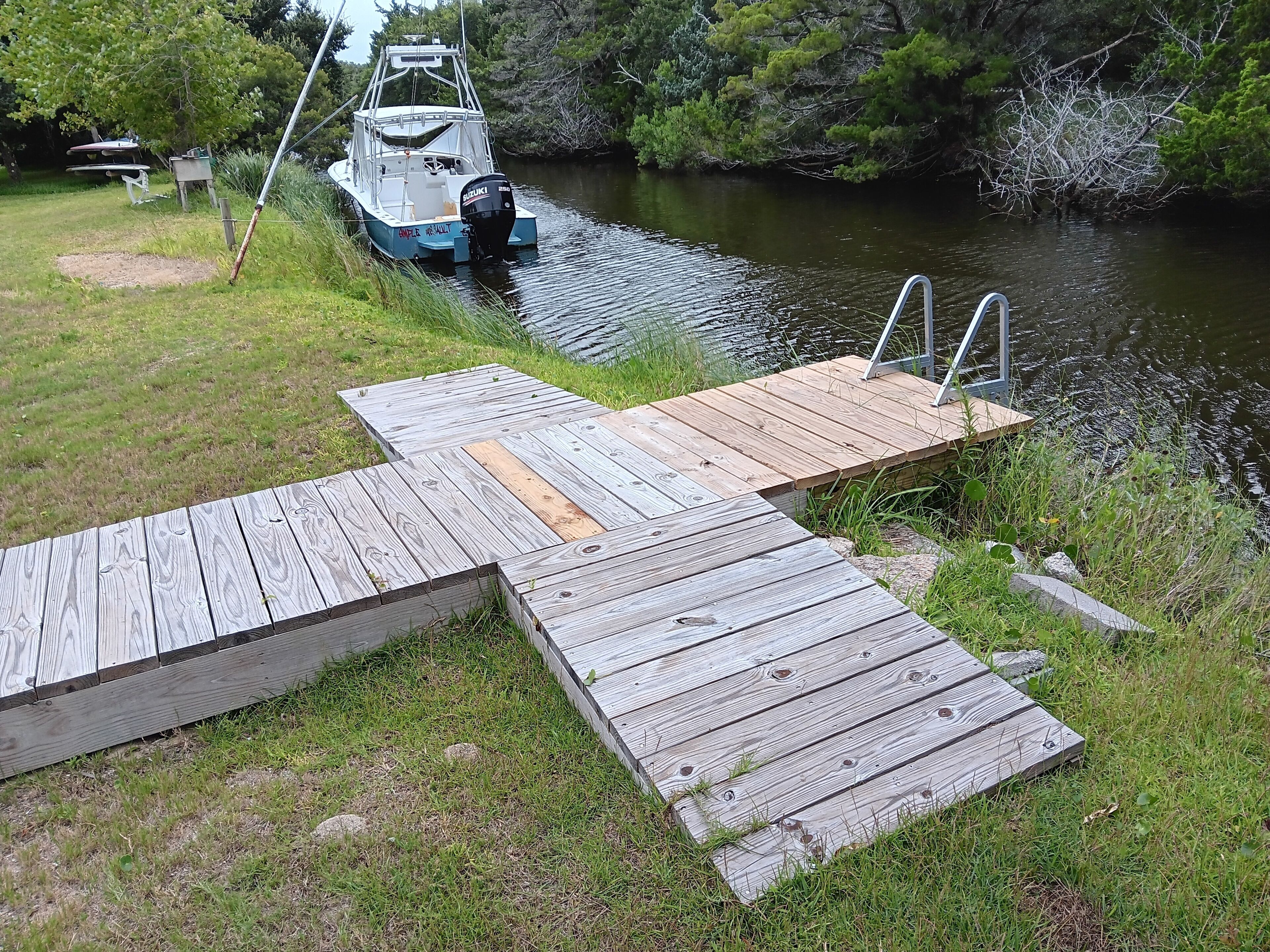 Un muelle de madera se extiende sobre un río, con un barco amarrado al final.
