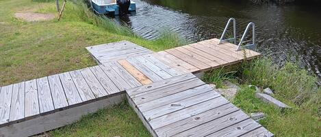 Un muelle de madera se extiende sobre un río, con un barco amarrado al final.