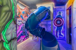 Une pièce avec un télescope, une fresque représentant des super-héros et une statue du Capitaine America.