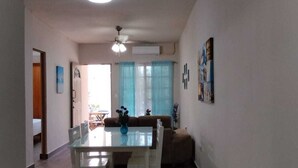 A spacious dining area with a white table and chairs, a ceiling fan, and a view of a living room with a sofa and curtains. - Charming villa in Tulum, near the Tulum Ruins. (Tulum)