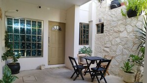 A patio area with a stone wall, a door, and a table with chairs. - Charming villa in Tulum, near the Tulum Ruins. (Tulum)