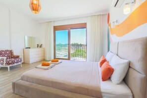 Un dormitorio con cama, cómoda, silla y balcón con vistas.