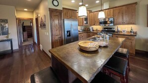 A spacious kitchen with wooden cabinets, a large island, stainless steel appliances, and pendant lighting. - Lakeview Getaway-Walk To Downtown Bigfork, Rated #1 Lake town in USA (Bigfork)