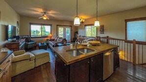 A spacious living area with a large island kitchen, a sofa, and a TV. - Lakeview Getaway-Walk To Downtown Bigfork, Rated #1 Lake town in USA (Bigfork)