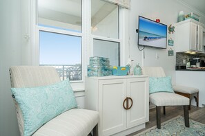 A room with two chairs, a white cabinet, a television, and a view of the beach. - Double size Balcony, Free Bikes,30 A between Aly’s & Rosemary, pool & hot tub. (Rosemary Beach)