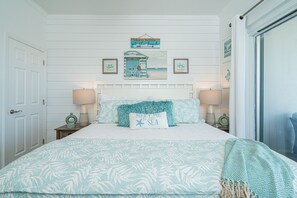 A bedroom with a bed, two nightstands, a headboard, and a wall with a beach-themed sign and framed pictures. - Double size Balcony, Free Bikes,30 A between Aly’s & Rosemary, pool & hot tub. (Rosemary Beach)