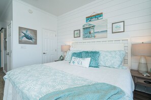 A bedroom with a large bed, a headboard, a nightstand, and a wall with a painting of a turtle. - Double size Balcony, Free Bikes,30 A between Aly’s & Rosemary, pool & hot tub. (Rosemary Beach)