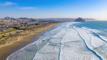 Un paysage urbain côtier avec une plage, des montagnes et un ciel dégagé.