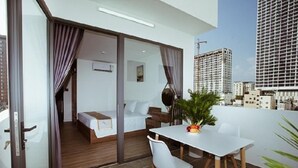 Ein modernes Hotelzimmer mit Balkon, einem Bett, einem kleinen Tisch und einer Zimmerpflanze.