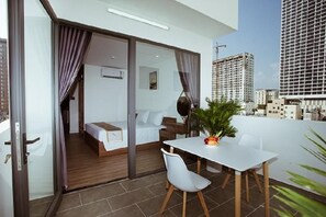 A modern hotel room with a balcony, a bed, a small table, and a potted plant. - Lee Charming Hotel by Zuzu (Nha Trang)