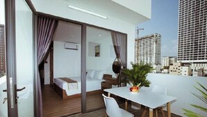 Ein modernes Hotelzimmer mit Balkon, einem Bett, einem Esstisch und einer Topfpflanze.