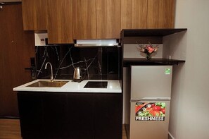 Eine kleine Küche mit Spüle, Wasserkocher und Kühlschrank.