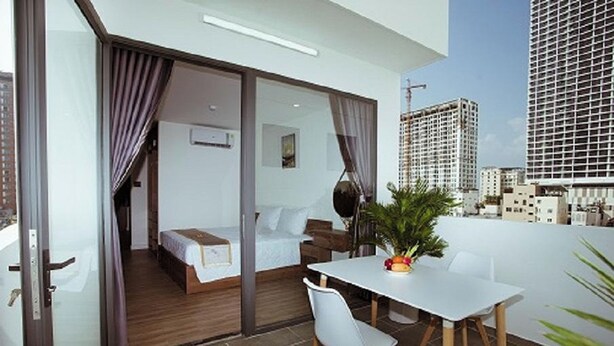 Ein modernes Hotelzimmer mit Balkon, Bett, Schreibtisch und Essecke.