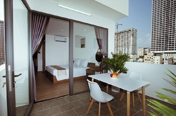 A modern hotel room with a balcony, a bed, a desk, and a dining area. - Lee Charming Hotel by Zuzu (Nha Trang)