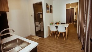 Een kleine keuken met een spoelbak en een eethoek met twee stoelen en een tafel.