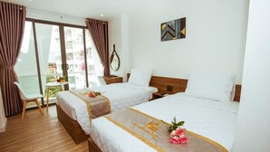 Een hotelkamer met twee bedden, een tafeltje, een stoel en uitzicht op het balkon.