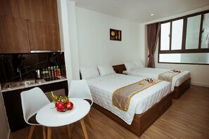 A hotel room with two beds, a small kitchenette, a dining area with a table and chairs, and a large window with curtains. - Lee Charming Hotel by Zuzu (Nha Trang)