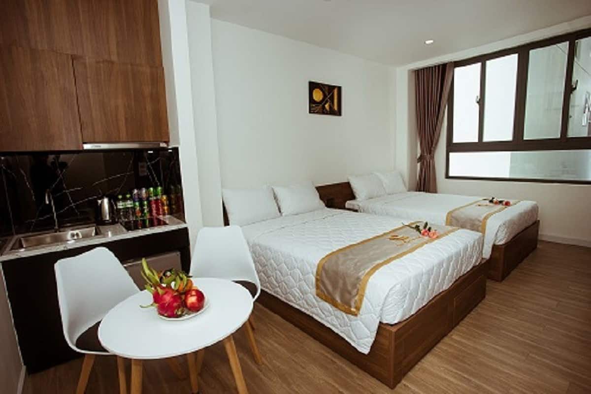 A hotel room with a bed, bedside tables, a small desk, a chair, and a window.