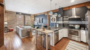 Una cocina moderna con una isla central, electrodomésticos de acero inoxidable y vistas a la ciudad a través de amplios ventanales.