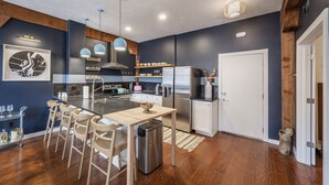 Una cocina moderna con una isla central, taburetes de bar, electrodomésticos de acero inoxidable y techo de madera.