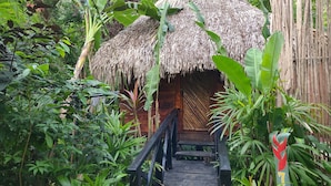 A wooden structure with a thatched roof, surrounded by lush greenery. - Samanatropicalvillage  (Samaná)