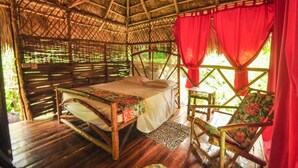 A room with a bed, a chair, and a thatched roof structure. - Samanatropicalvillage  (Samaná)