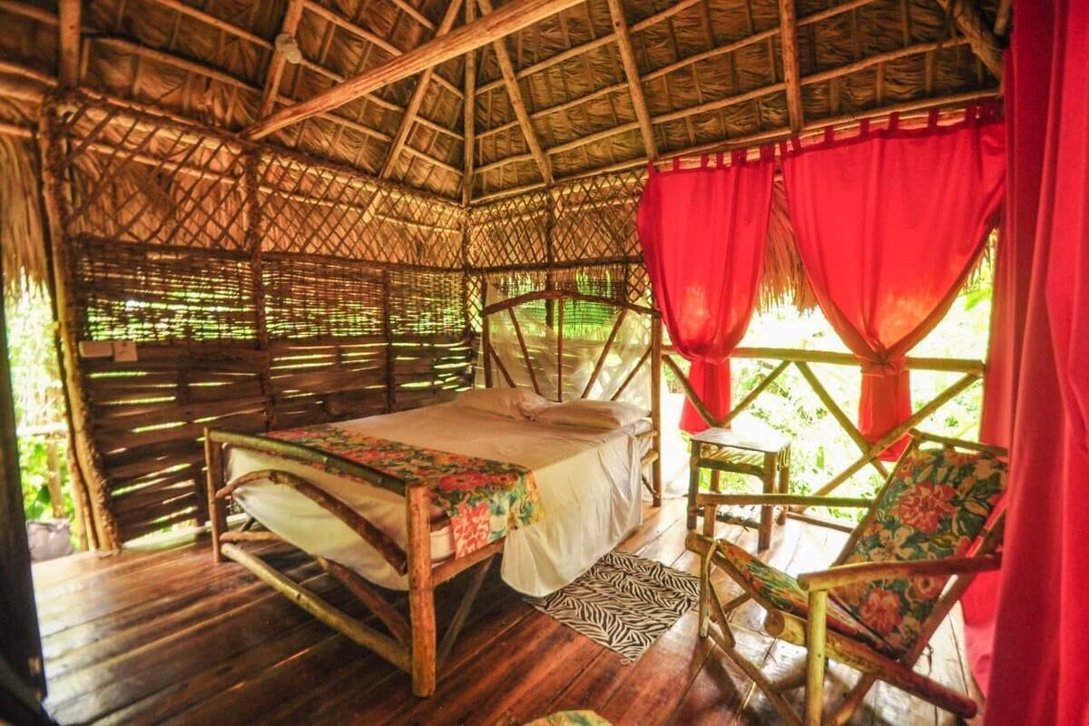 Una habitación con una cama, una silla y un techo de paja.