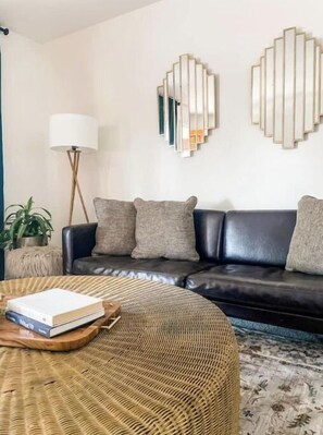 Relax in this stylish living room with a dark leather sofa, woven ottoman, and floor lamp.