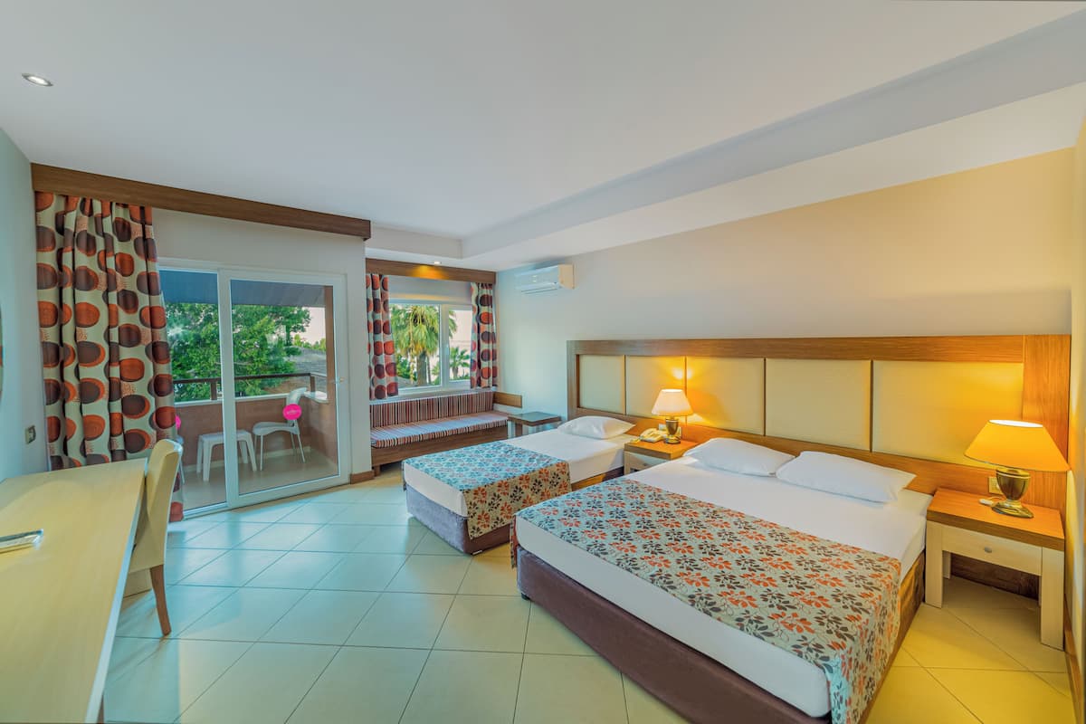 Une chambre d’hôtel avec deux lits, un bureau, une chaise, un balcon avec vue et une porte coulissante.