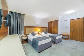 A hotel room with two beds, a desk, a TV, and a wardrobe. - Justiniano Club Alanya (Alanya)