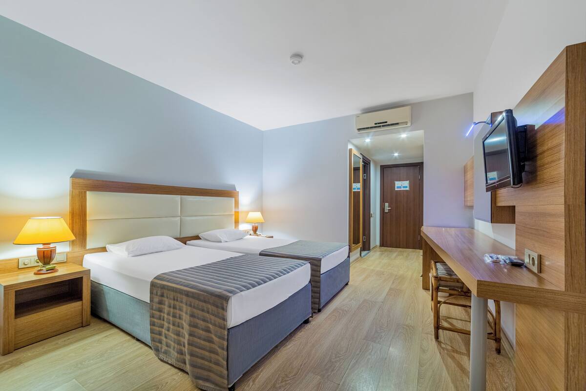 Une chambre d’hôtel avec deux lits, un bureau, une télévision et un appareil de climatisation.