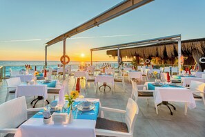 Een terras met tafels gedekt voor een maaltijd, met uitzicht op zee.