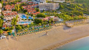 An aerial view of a coastal resort with a beach, pool, and multiple hotel buildings. - Justiniano Club Alanya (Alanya)