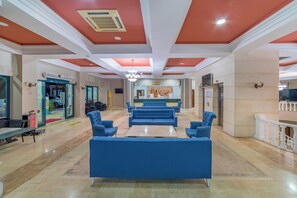 A spacious lobby with blue sofas, a reception desk, and a chandelier. - Justiniano Club Alanya (Alanya)
