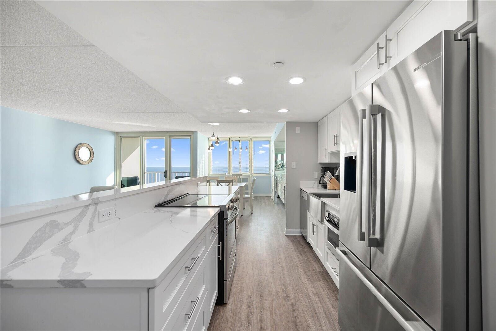 A modern kitchen with a large island, stainless steel appliances, and a view to the outside.
