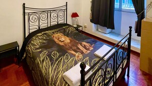 Une chambre à coucher avec un lit, une fenêtre avec des rideaux, une table de chevet et une lampe.