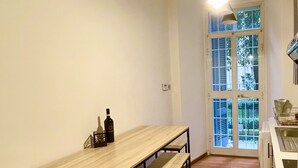 Une cuisine avec une longue table et des bancs en bois, un luminaire suspendu et une fenêtre donnant sur un paysage verdoyant.