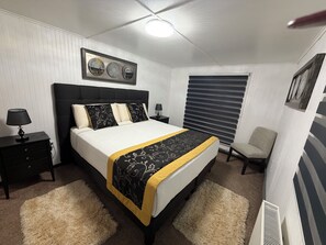A bedroom with a bed, bedside tables, a chair, a window with blinds, and a ceiling light. - HOTEL FORJADORES DEL CABO DE HORNOS (Cabo de Hornos)