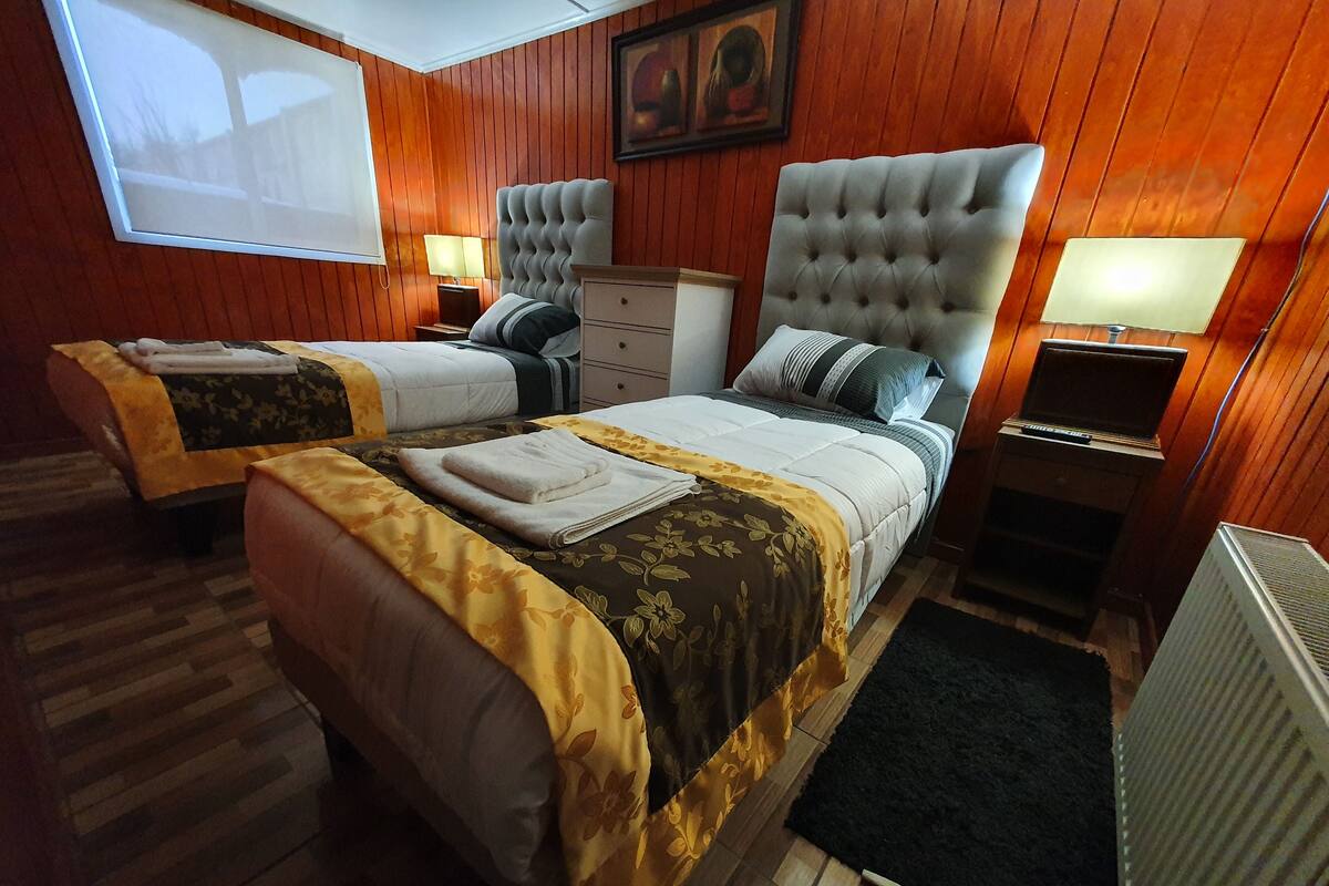 Ein Hotelzimmer mit zwei Betten, einem Schreibtisch, einem Stuhl, einem Heizkörper und einem Fenster.