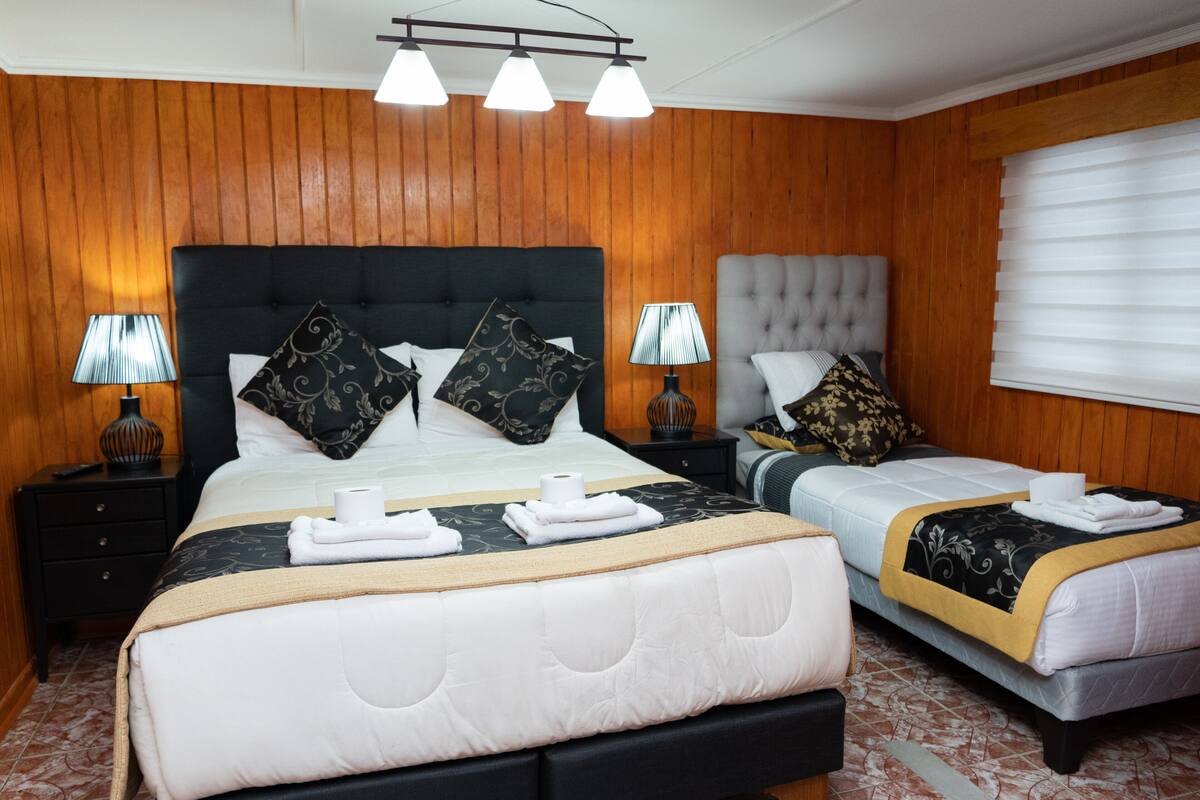 Ein Hotelzimmer mit zwei Betten, Holzvertäfelung und einem großen Fenster mit Jalousien.